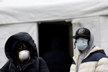 شخصان يرتديان كمامتان للوقاية من كورونا ويقفان بجانب خيمة للاختبار من الفيروس بمستشفى في بروكلين بنيويورك الخميس