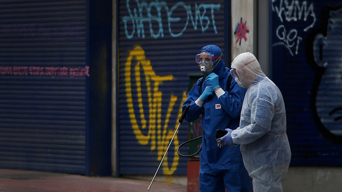 Workers wearing protective suits walk in central Athens to spray disinfectant, Sunday, March 22, 2020. (AP)
