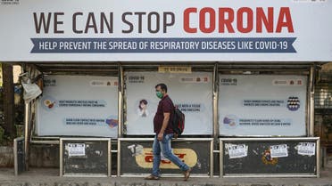 A man wearing a protective mask walks past a bus stop displaying preventive measures against the coronavirus in Mumbai, India, March 18, 2020. (Reuters)