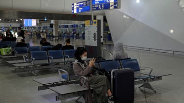 A passenger wearing a protective face mask checks her phone at the Athens International airport, following an outbreak of the coronavirus disease (COVID-19), in Athens, Greece, March 21, 2020. REUTERS/Alkis Konstantinidis
