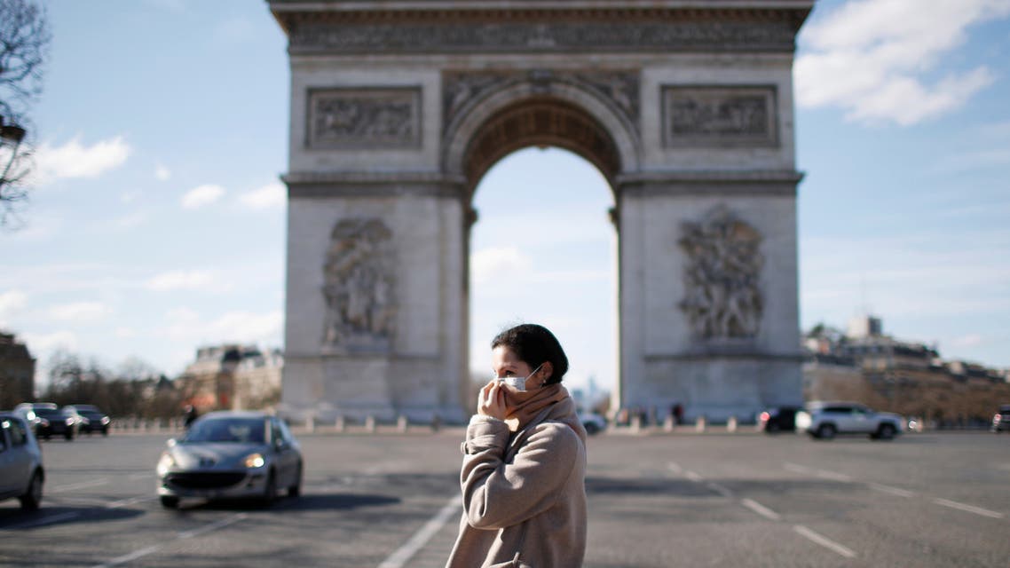 امراة تضع كمامة تسير بالقرب من قوس النصر في باريس
