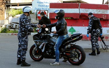 Lebanese security forces stop a man on a bike for violating coronavirus measures in central Beirut, March 22. (Reuters)