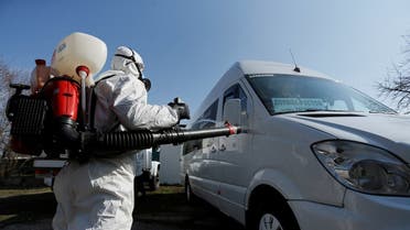 A worker wearing a protective suit sprays disinfectant on a bus as a preventive measure against the spread of coronavirus disease (COVID-19) in Donetsk. (Reuters)