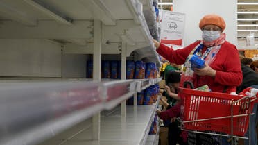 A woman, wearing a protective mask, holds a pack of buckwheat from a new delivery, next to empty shelves in a section for cereals and groats, in a supermarket in Moscow, Russia on March 19, 2020. (Reuters)