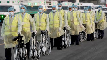 Health ministry workers, wearing protective outfits, wait on the tarmac of the Kuwait international Airport to receive Kuwaitis returning from Frankfurt on March 26, 2020, to be taken to a hospital for novel coronavirus checkups, in the capital Kuwait City.