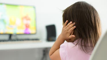 A terrified child, afraid of the loud sounds from the television. Autism. stock photo