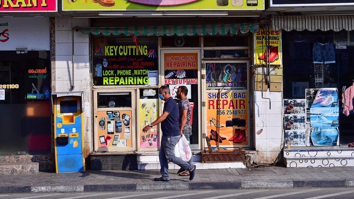 Mask-clad men walk by a closed shop in Dubai amid measures to curb the spread of coronavirus (COVID-19), on March 25, 2020. (AFP)