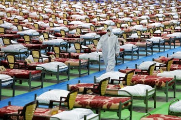 People in protective clothing walk past rows of beds at a temporary 2,000-bed hospital for COVID-19 patients set up by the Iranian army in northern Tehran, Iran, on Thursday, March 26, 2020. (AP)