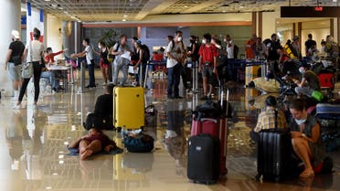 Stranded tourists (foreground) gather as French embassy staff (background L, at tables) process nationals ahead of their evacuation flight amid concerns from the COVID-19 coronavirus at the Ngurah Rai international airport near Denpasar. (AFP)