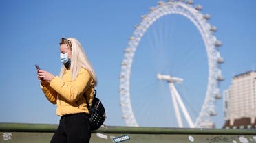 A pedestrian in a mask walks along Westminster Bridge with the London Eye in the backgroud, in a quiet central London on March 25, 2020, after Britain's government ordered a lockdown to slow the spread of the novel coronavirus. Britain was under lockdown, its population joining around 1.7 billion people around the globe ordered to stay indoors to curb the accelerating spread of the coronavirus.
