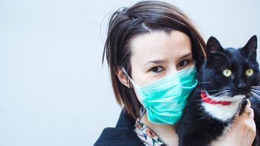 A young woman in a protective mask holding a cat in her arms stock photo stock photo