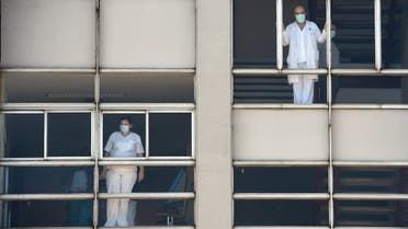 Healthcare workers dealing with the new coronavirus crisis look through the windows of the University Hospital in Coruna, northwestern Spain, on March 26, 2020. Spain's coronavirus death toll surged above 4,000 today but the increase in both fatalities and new infections slowed, leaving officials hopeful a nationwide lockdown is starting to curb the spread of the disease. A total of 655 deaths were recorded in the country in the last 24 hours, bringing the toll to 4,089, the health ministry said.