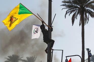 A member of Hashd al-Shaabi holds a flag of Kataib Hezbollah militia group during a protest to condemn air strikes on their bases, in Baghdad. (File photo: Reuters)