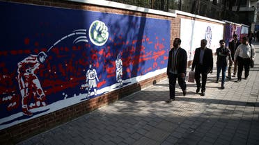 People walk in front of new murals of the former US embassy in Tehran, Iran. (Reuters)