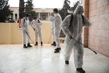 Members of a humanitarian aid agency disinfect Ibn Sina hospital as prevention against coronavirus in the city of Idlib, Syria, on March 19, 2020. (AP)