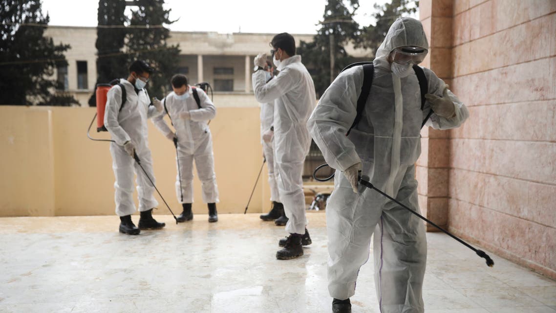 Members of a humanitarian aid agency disinfect Ibn Sina hospital as prevention against coronavirus in the city of Idlib, Syria, on March 19, 2020. (AP)