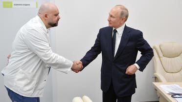 A picture taken on March 24, 2020 shows Russian President Vladimir Putin (R) shaking hands with the head of Moscow's new hospital treating coronavirus (COVID-19) patients Denis Protsenko. (AFP)