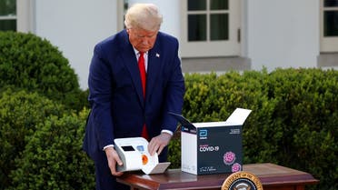 US President Donald Trump examines a coronavirus testing kit as he prepares to speak during the daily coronavirus response briefing in the Rose Garden at the White House in Washington, US, March 30, 2020. (Reuters) 