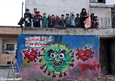 Syrian artist Aziz Asmar with children in Idlid above one of his coronavirus murals. (Mohamad Jamalo)