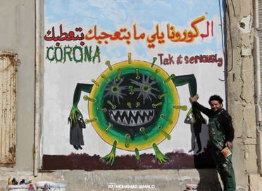 Syrian artist Aziz Asmar with a coronavirus mural in Idlib. (Mohamad Jamalo)