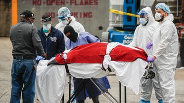 A body wrapped in plastic that was unloaded from a refrigerated truck is handled by medical workers wearing personal protective equipment. (AP)
