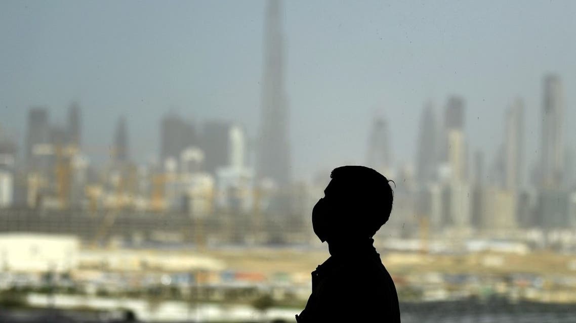 A man wearing a protective mask stands at a racetrack overlooking Dubai following the UAE's decision to postpone the upcoming Dubai Horse Racing amid the COVID-19 coronavirus pandemic, on March 23, 2020 in Dubai. (AFP)