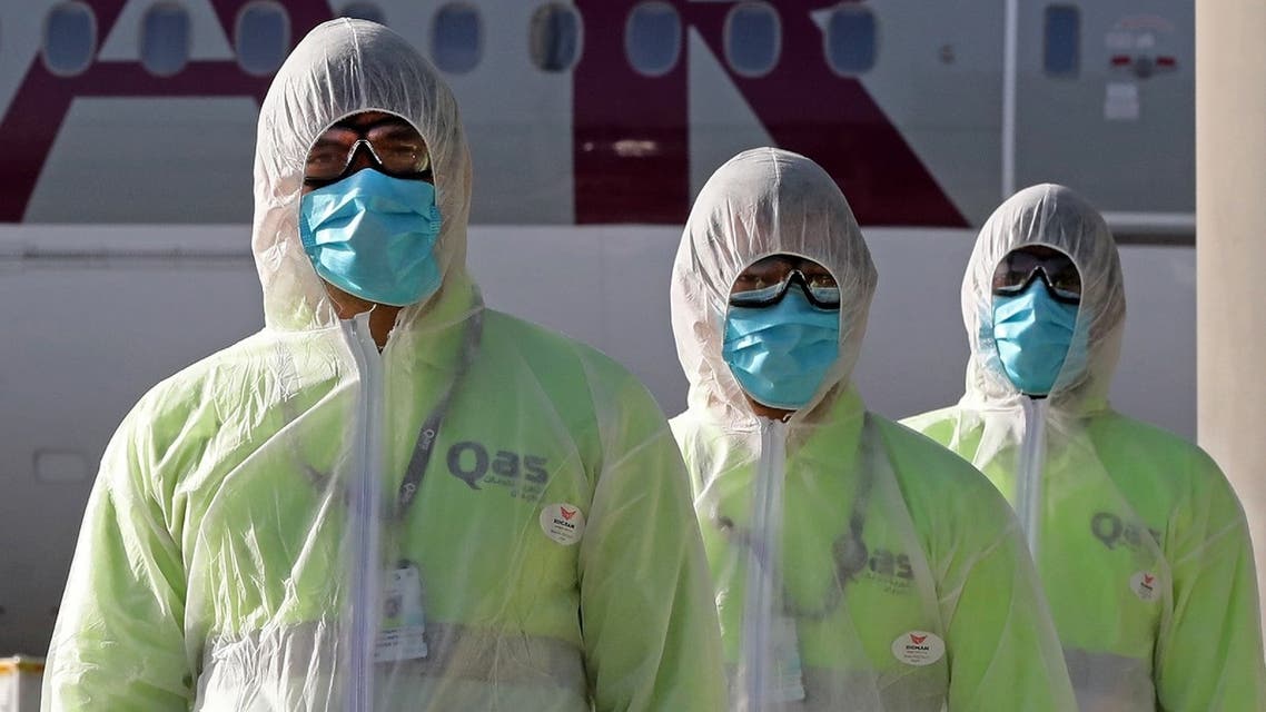 Employees of Qatar Aviation Services (QAS), wearing protective gear as a safety measure during the COVID-19 coronavirus pandemic, walk along the tarmac after sanitizing an aircraft at Hamad International Airport in the Qatari capital Doha on April 1, 2020. (AFP)