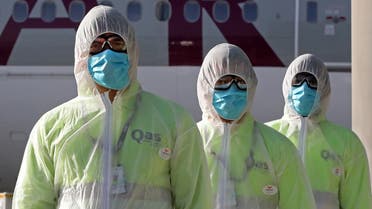 Employees of Qatar Aviation Services (QAS), wearing protective gear as a safety measure during the COVID-19 coronavirus pandemic, walk along the tarmac after sanitizing an aircraft at Hamad International Airport in the Qatari capital Doha on April 1, 2020. (AFP)
