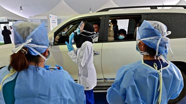 A nurse instructs a driver about the procedure of the coronavirus testing in front of a drive thru verification center in the Emirati capital Abu Dhabi on April 2, 2020. (AFP)