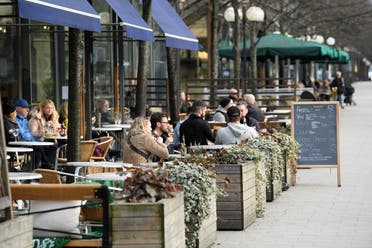 People sit at an outdoor restaurant in Kungstradgarden park amid the new coronavirus spread, in Stockholm, Sweden March 27, 2020. (Reuters)