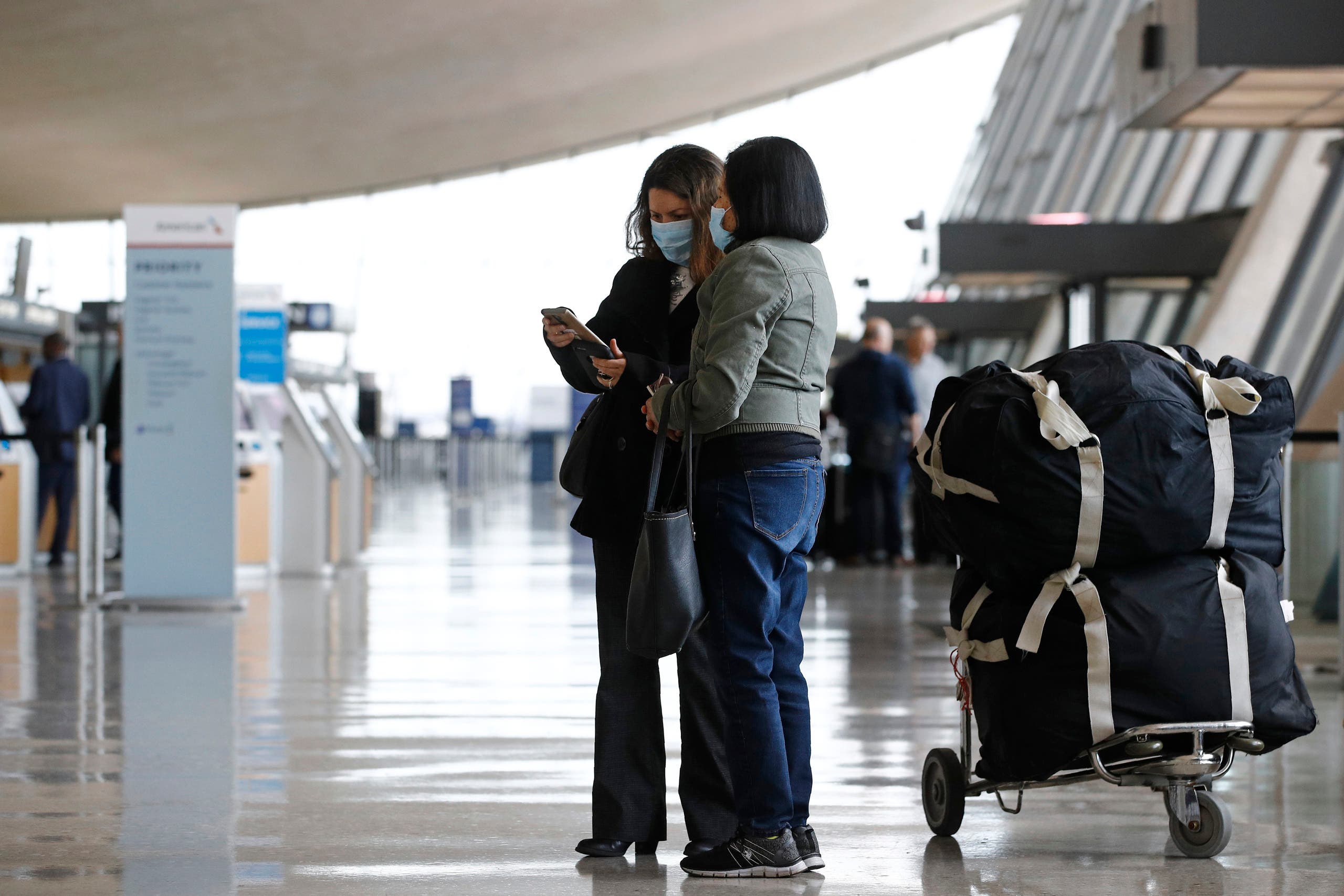 Travelers wear face masks as they prepare to check in for a flight at Dulles International Airport in Dulles, Va., Tuesday, March 17, 2020. (AP)
