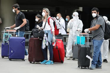 Lebanese people, who were stranded abroad by coronavirus lockdowns, are pictured wearing face masks and gloves as they hold their luggage upon arrival at Beirut's international airport on April 5, 2020.(Reuters)