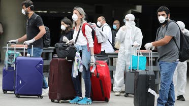Lebanese people, who were stranded abroad by coronavirus lockdowns, are pictured wearing face masks and gloves as they hold their luggage upon arrival at Beirut's international airport, Lebanon. (Reuters)