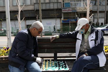 Men wear protective face masks and gloves, amid fear of coronavirus, play chess on the sidewalk of Mellat Park, in Tehran, Iran April 2, 2020. (WANA (West Asia News Agency)/Ali Khara via Reuters)