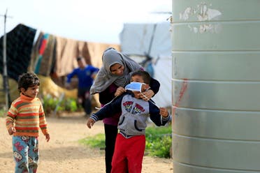 A Syrian refugee woman puts a face mask on a boy as a precaution against the spread of coronavirus, in al-Wazzani area in southern Lebanon. (File photo: Reuters)