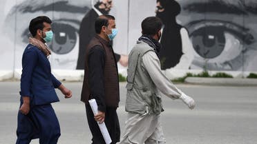 Men wearing facemasks as a precautionary measure against the COVID-19 novel coronavirus walk past a wall painted with images of US Special Representative for Afghanistan Reconciliation Zalmay Khalilzad (L) and Taliban co-founder Mullah Abdul Ghani Baradar (R), in Kabul April 5, 2020. 