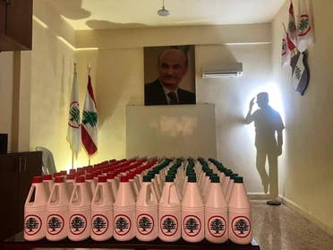 An image shows bottles of sanitizer with the Lebanese Forces political party's logo on neatly arranged in a room with LF leader Samir Geagea's portrait in the background. (Facebook, HEY Lubnan)