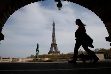 A woman walks her dog on a Paris bridge, with the Eiffel tower seen in background, during a nationwide confinement to counter COVID-19 on Tuesday, April 7, 2020. (AP)