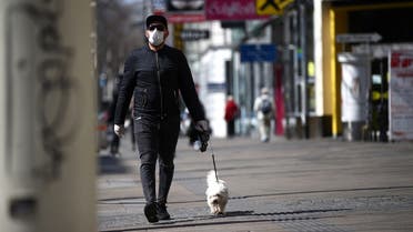 A man wearing a protective mask walks a dog on a shopping street during the global coronavirus disease (COVID-19) outbreak in Vienna. (Reuters)