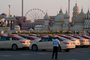 A security guard keeps watch over hundreds of taxi cabs parked at the shopping theme park Global Village in Dubai, United Arab Emirates,  on Tuesday, April 7, 2020.  (AP)