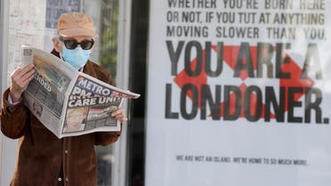 A man in the UK reads the newspaper a headline about Boris Johnson being in hospital against the backdrop of a sign which says You are a Londoner. (AP)