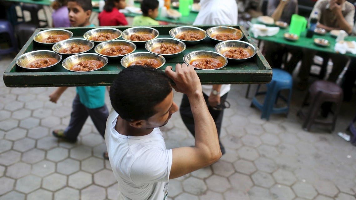 A volunteer carries food to tables as people wait to eat their Iftar meal during the holy fasting month of Ramadan in Cairo. (Reuters)