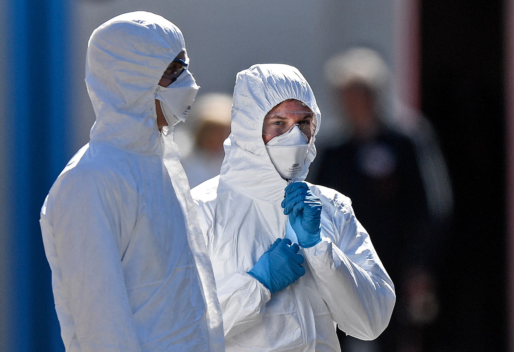 Employees wearing protective clothings wait in the warm sun for the next patient at a coronavirus test station outside the hospital 'Klinikum Nord' in Dortmund, Germany on April 4, 2020. (AP)