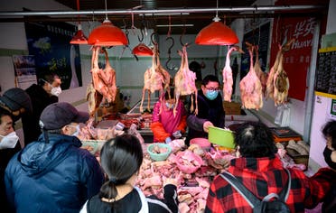 People wearing protective face masks shop at a chicken stall at a wet market in Shanghai on February 13, 2020.  (AFP)