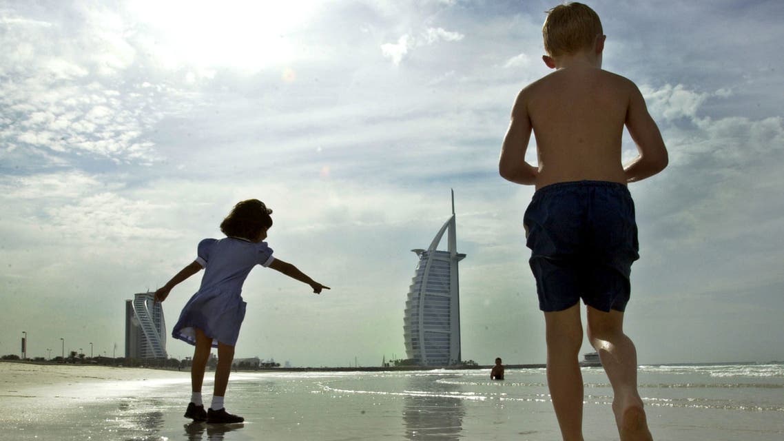 With the Burj Al Arab, seven star luxury hotel in the background, a girl points out a baby crab to other children as they play on the beach in in Dubai, United Arab Emirates, Thursday, Dec. 9, 2004. (AP)