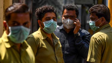 People wearing facemasks amid concerns over the spread of the COVID-19 novel coronavirus stand outside a hospital with a special ward for the virus in Mumbai on March 17, 2020. (AFP)