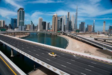 A lone taxi cab drives over a typically gridlocked highway with the Burj Khalifa, the world's tallest building, in the skyline behind it in Dubai, United Arab Emirates on April 6, 2020. (AP)