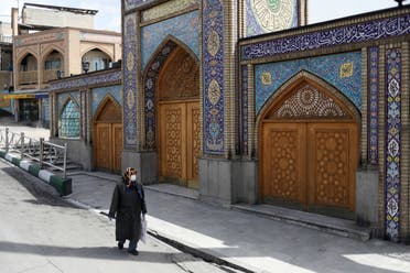 A woman wearing a protective face mask and gloves walks past the Imamzadeh Saleh shrine, amid fear of the coronavirus disease (COVID-19), in Tehran, Iran April 2, 2020. (Reuters)