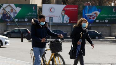 Syrians wearing face masks walk in front of posters informing about the novel coronavirus, in the capital Damascus on April 1, 2020. 