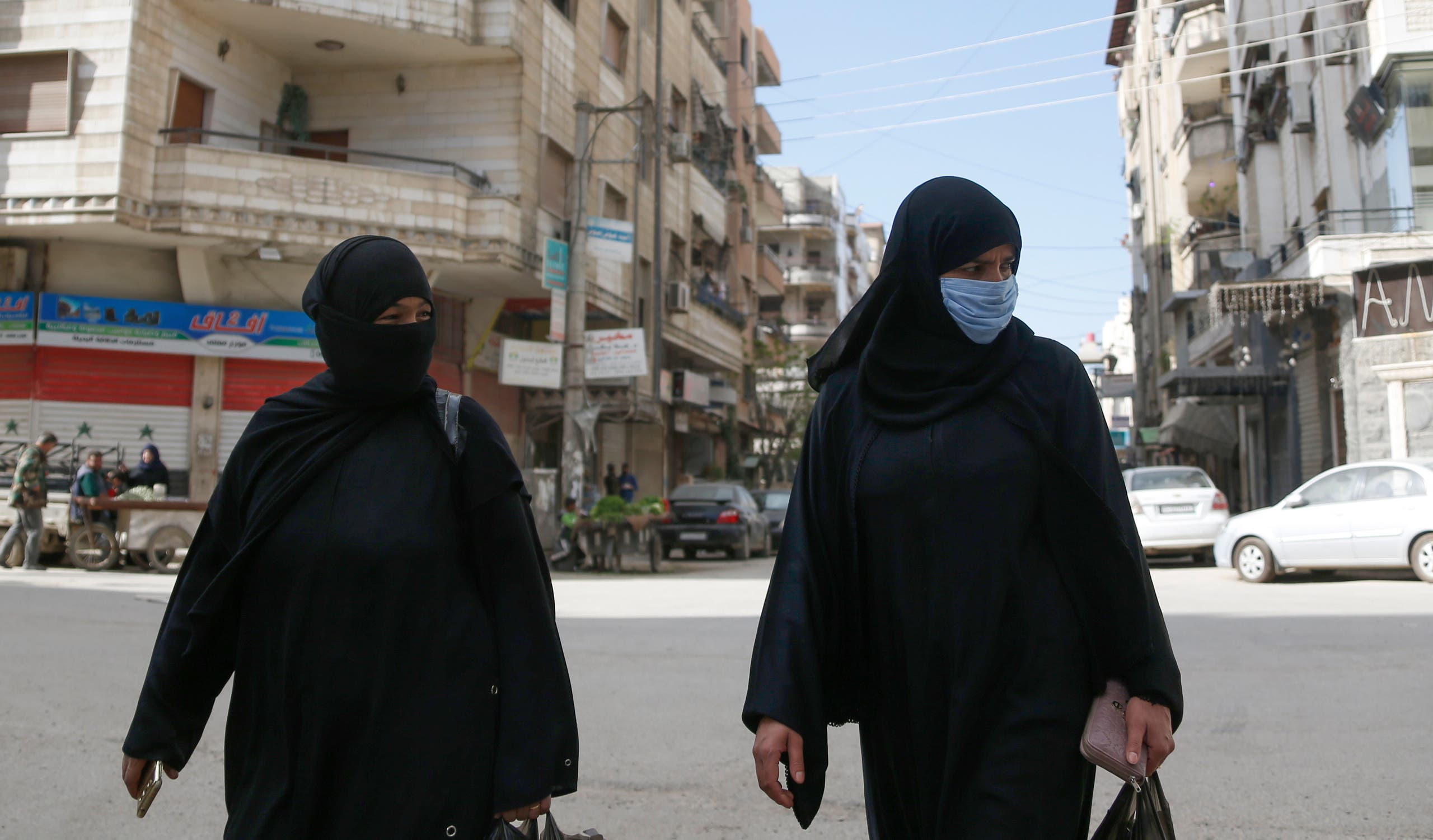 Syrian women, one of them wearing a face mask as a preventive measure against the novel coronavirus, walk along a street in the capital Damascus on April 1, 2020. (AP)